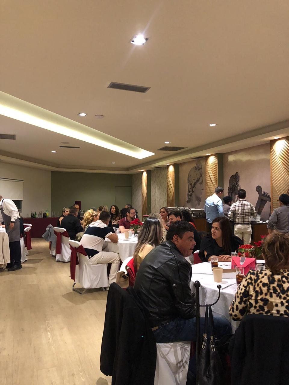 Asistentes conversando en una cena con mesas vestidas de blanco y rojo