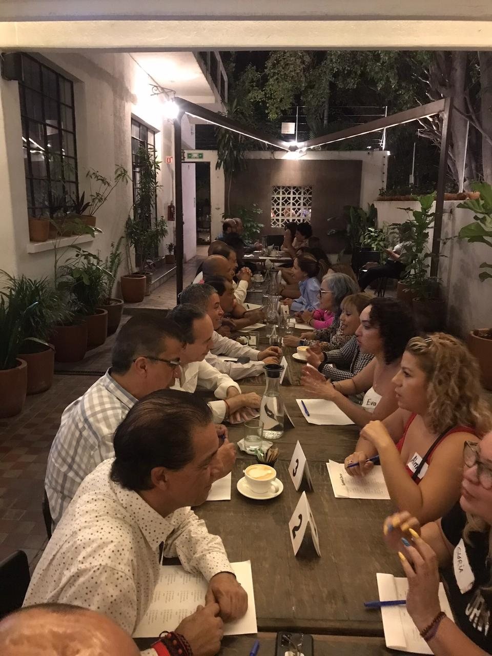 Personas conversando en una mesa larga durante un evento de citas